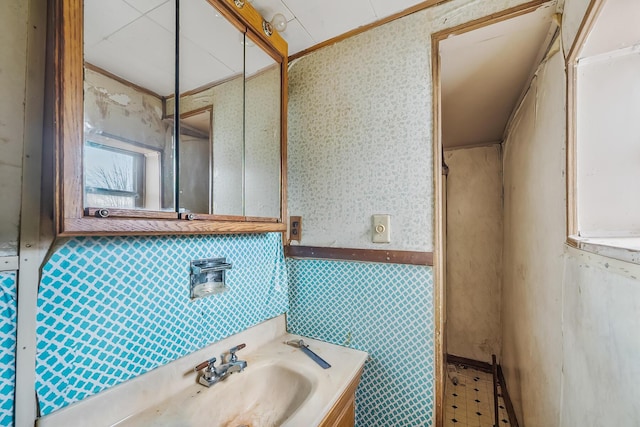 bathroom with tile patterned floors, ornamental molding, vanity, and wallpapered walls