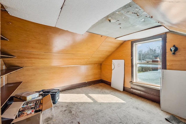 additional living space featuring vaulted ceiling, wooden walls, and light colored carpet