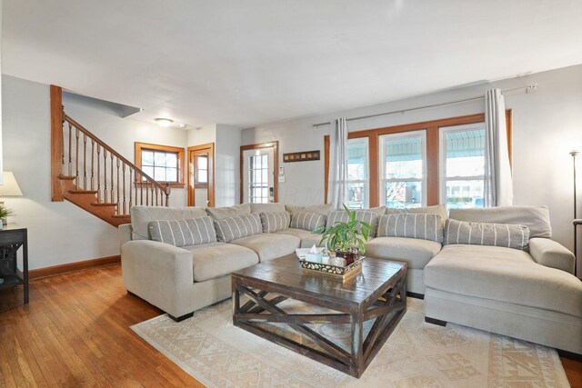 living area featuring stairway, baseboards, and light wood-style floors