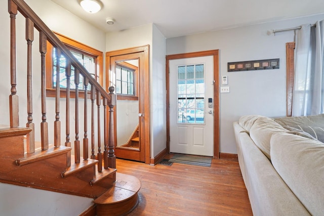 foyer entrance with stairs, baseboards, and light wood finished floors