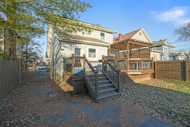 rear view of house with a deck, a gate, a fenced backyard, and a pergola