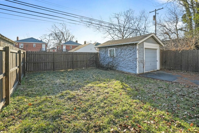 view of yard featuring a garage, a fenced backyard, and an outdoor structure