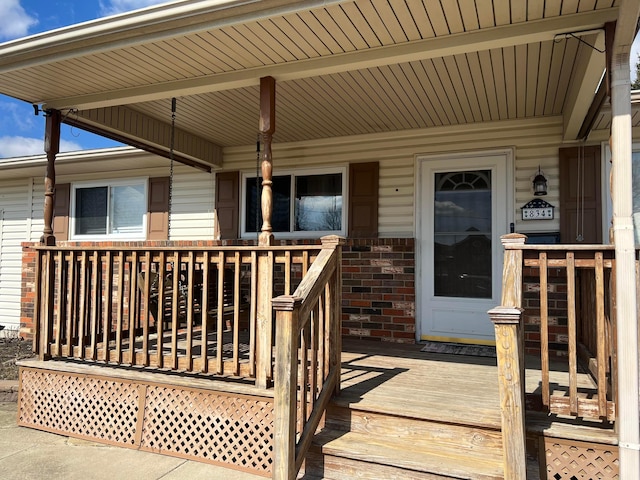 entrance to property with brick siding and a porch