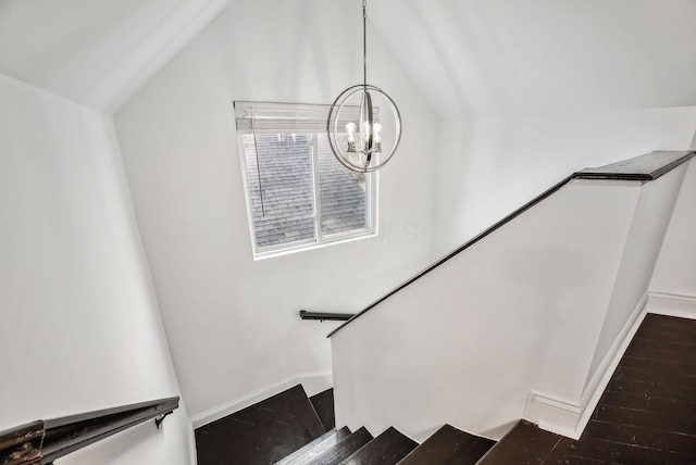 stairs with vaulted ceiling, wood finished floors, baseboards, and a chandelier