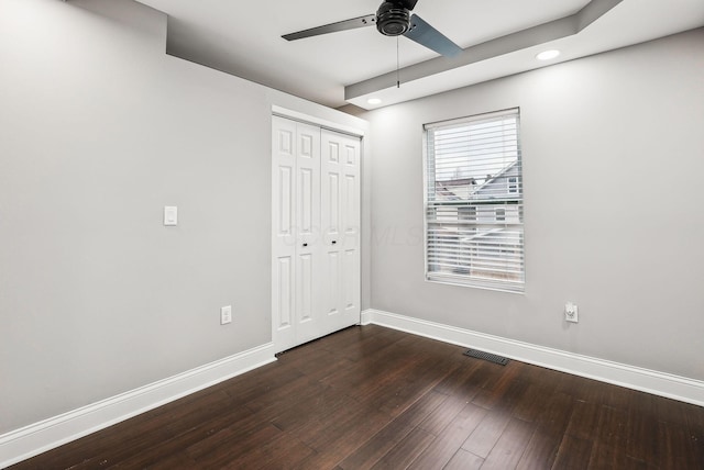 unfurnished bedroom featuring dark wood finished floors, visible vents, a closet, and baseboards