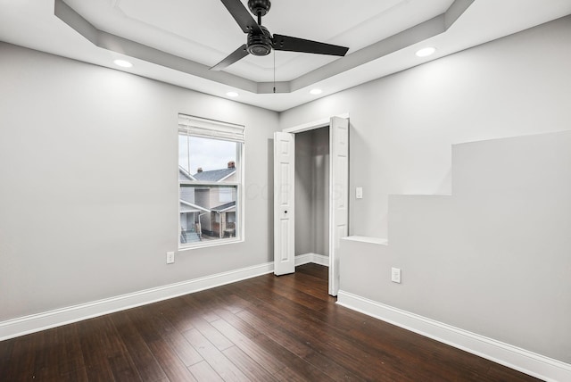 unfurnished bedroom with ceiling fan, baseboards, hardwood / wood-style floors, recessed lighting, and a raised ceiling