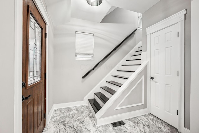 foyer with stairway, marble finish floor, and baseboards