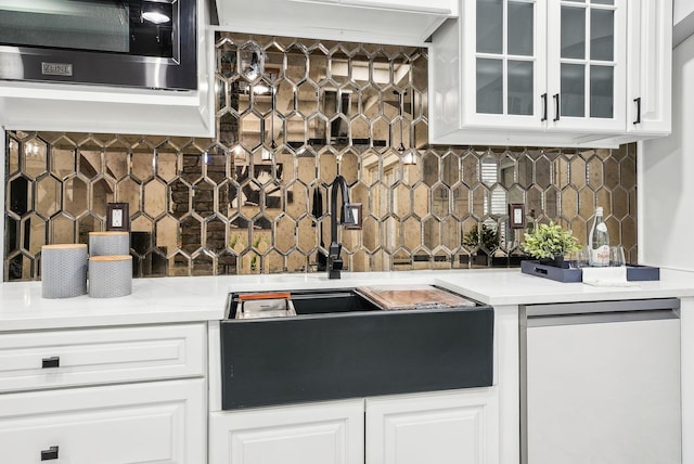 kitchen featuring a sink, glass insert cabinets, tasteful backsplash, and white cabinets