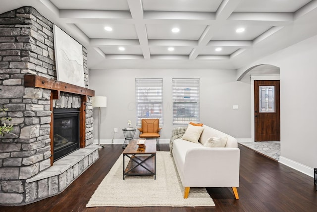 living room featuring baseboards, arched walkways, dark wood-type flooring, and a fireplace