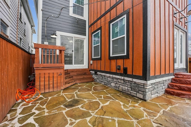 view of side of home with fence, a patio area, and board and batten siding