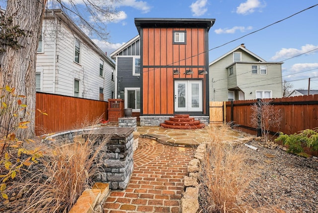 rear view of property featuring entry steps, board and batten siding, a fenced backyard, and a patio area