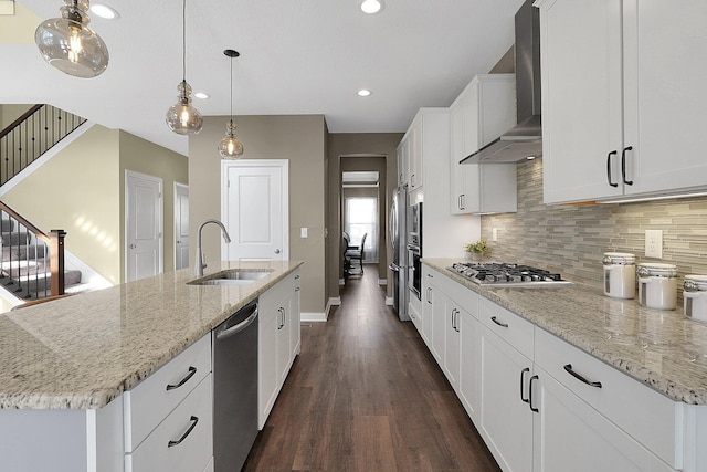 kitchen with dark wood finished floors, a sink, appliances with stainless steel finishes, wall chimney exhaust hood, and tasteful backsplash