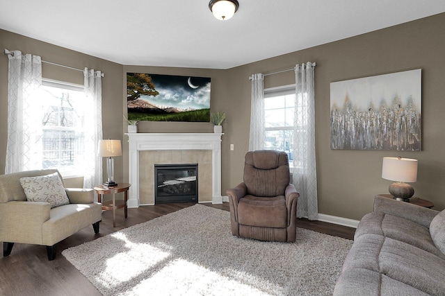 living area with a tiled fireplace, wood finished floors, and baseboards