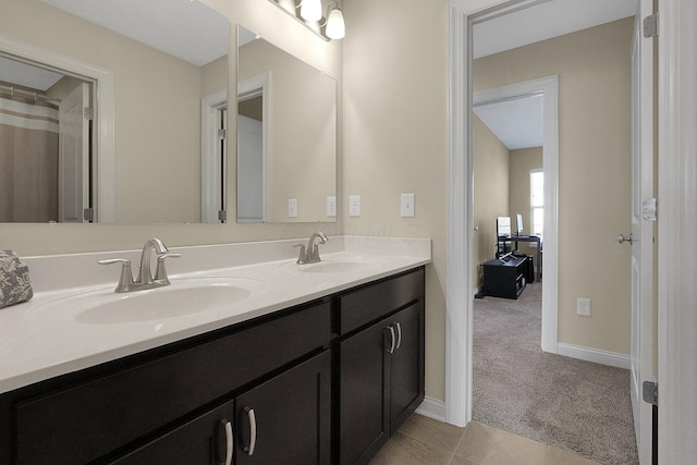 full bath with double vanity, tile patterned floors, baseboards, and a sink