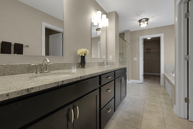 full bathroom featuring a sink, a walk in closet, double vanity, and tile patterned floors