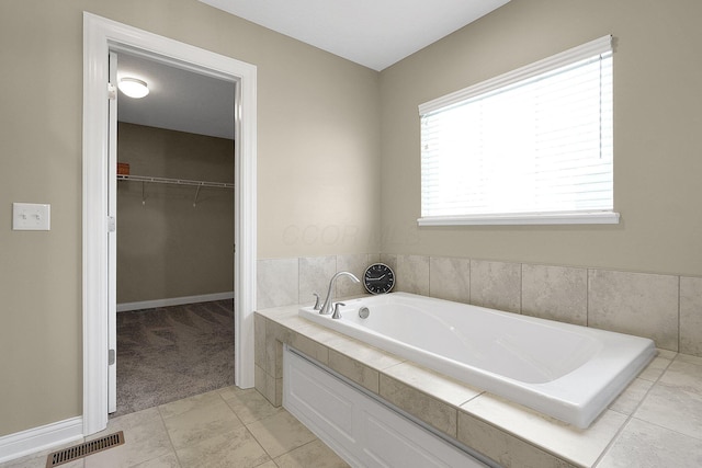 full bathroom with visible vents, a garden tub, and a spacious closet