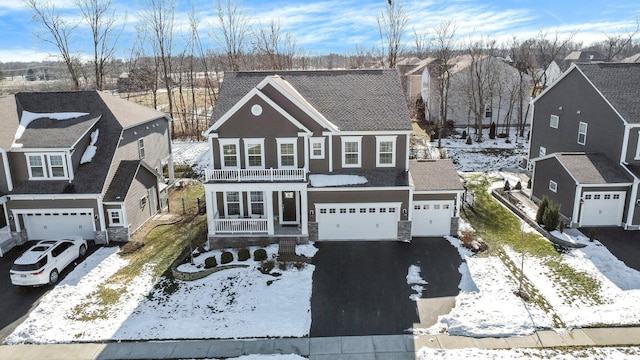 traditional home featuring aphalt driveway, a residential view, a porch, a balcony, and an attached garage