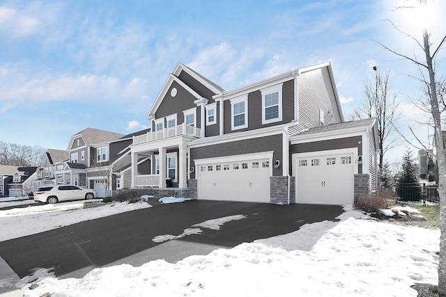 view of property featuring stone siding, driveway, a residential view, and a balcony