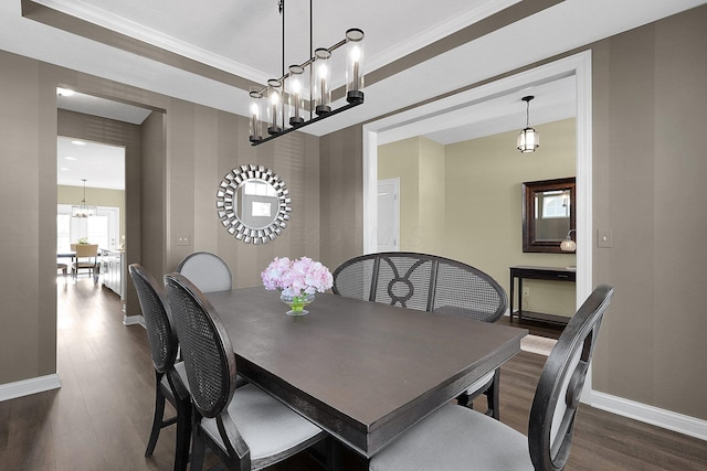 dining area featuring an inviting chandelier, baseboards, dark wood-style flooring, and ornamental molding