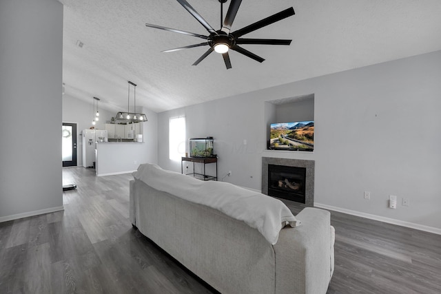 living room with dark wood finished floors, a fireplace, ceiling fan, vaulted ceiling, and a textured ceiling