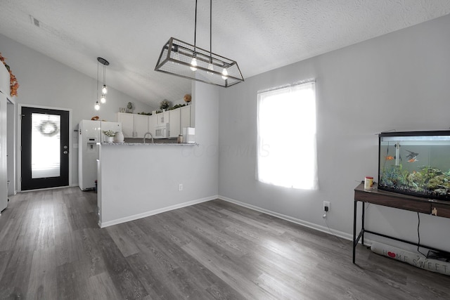 interior space featuring wood finished floors, a textured ceiling, baseboards, and vaulted ceiling