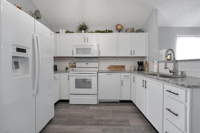 kitchen with a sink, white appliances, and white cabinets