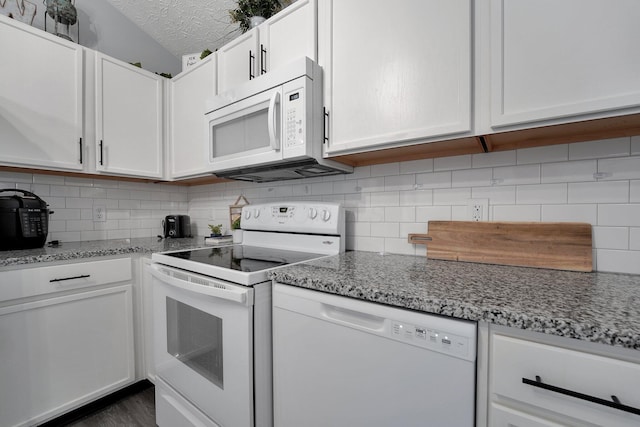 kitchen featuring white cabinetry, white appliances, light stone countertops, and backsplash