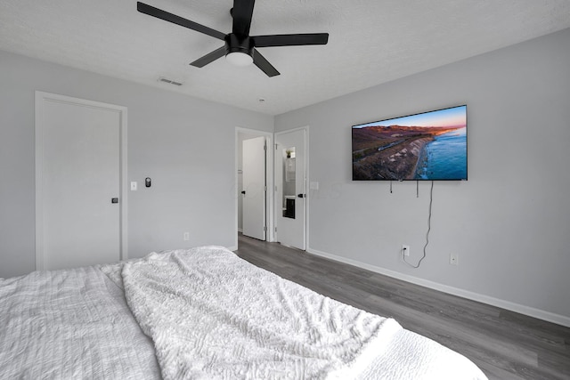 bedroom featuring visible vents, ceiling fan, baseboards, wood finished floors, and a textured ceiling