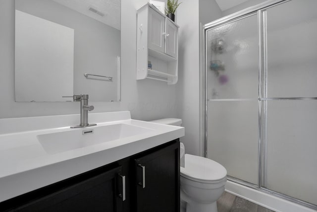 full bathroom featuring wood finished floors, toilet, visible vents, and a stall shower