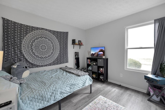 bedroom with baseboards, a textured ceiling, and wood finished floors