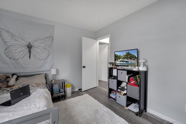 bedroom with baseboards, a textured ceiling, and wood finished floors