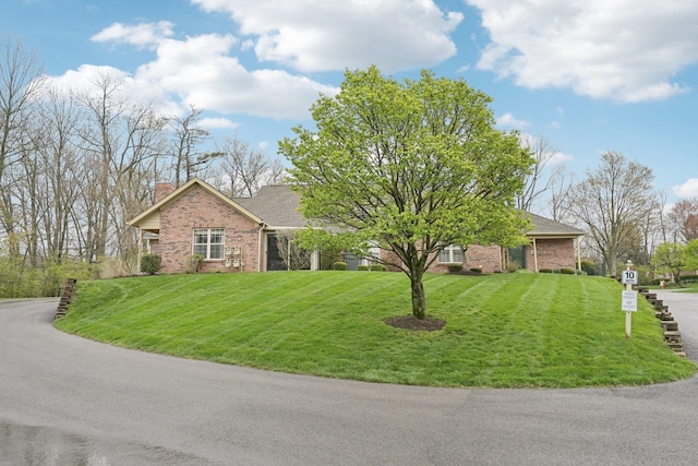 single story home with roof with shingles, a chimney, a front yard, and brick siding
