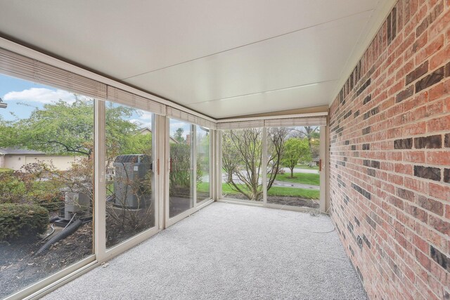 unfurnished sunroom featuring carpet flooring and brick wall