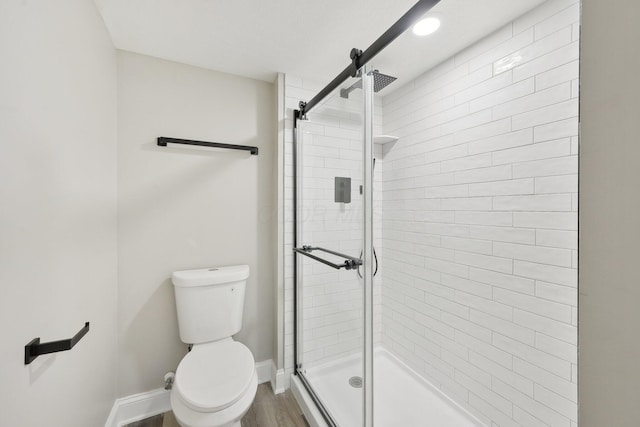 full bathroom featuring toilet, a stall shower, wood finished floors, and baseboards