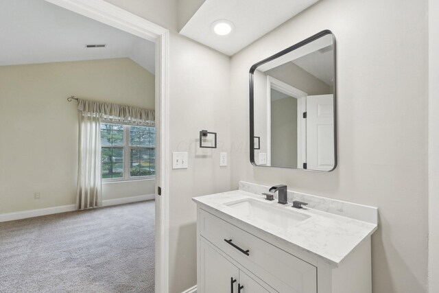 bathroom with visible vents, baseboards, vanity, and lofted ceiling