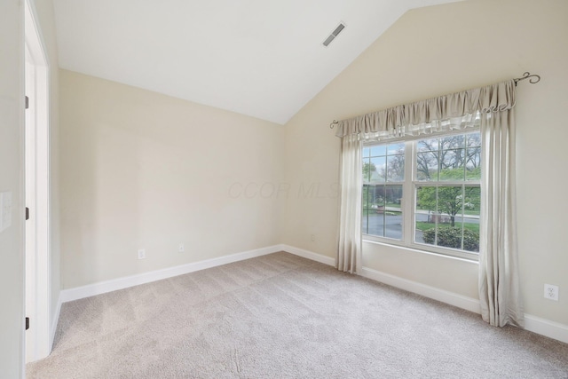 carpeted spare room with baseboards, vaulted ceiling, and visible vents