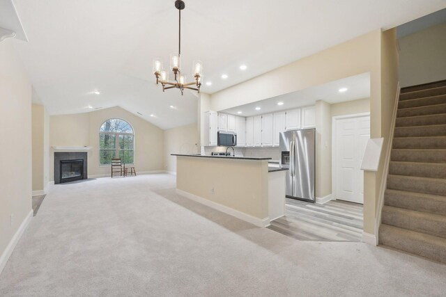 kitchen featuring dark countertops, white cabinetry, stainless steel appliances, pendant lighting, and light carpet