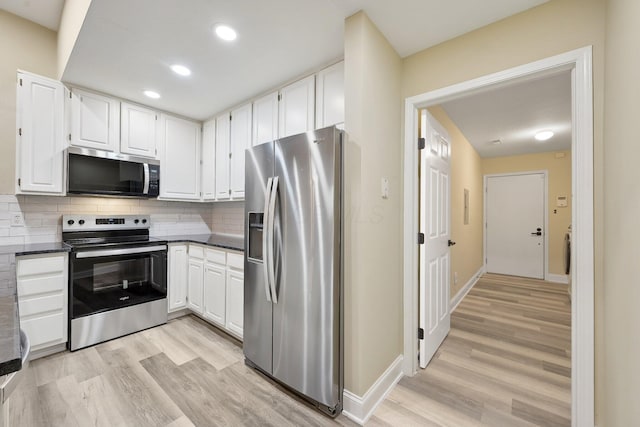 kitchen with stainless steel appliances, light wood-style flooring, white cabinetry, and dark countertops