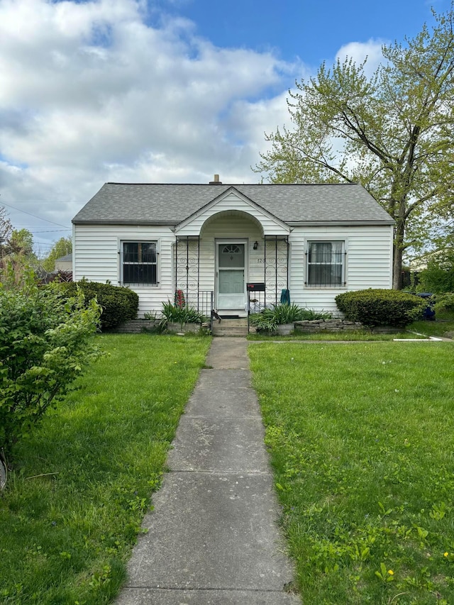 view of front of house with a shingled roof and a front yard