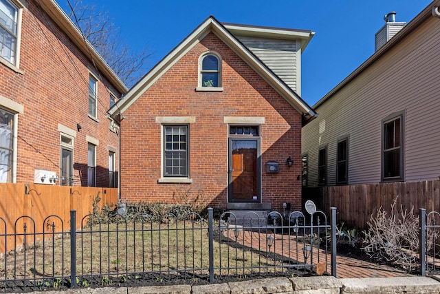 view of front facade featuring brick siding and a fenced front yard