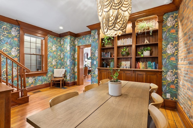 dining space with ornamental molding, hardwood / wood-style flooring, stairway, wallpapered walls, and baseboards