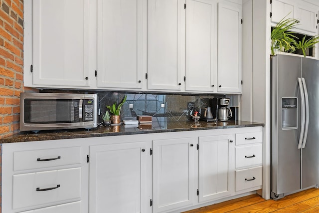 kitchen featuring white cabinetry, decorative backsplash, dark stone countertops, and appliances with stainless steel finishes