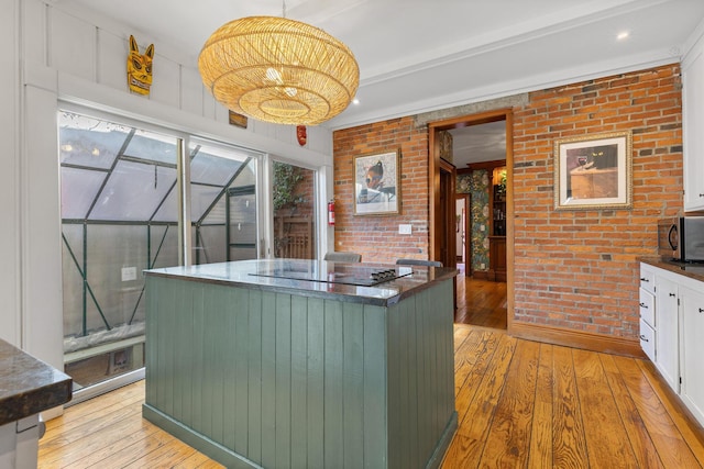 kitchen featuring dark countertops, brick wall, and light wood finished floors