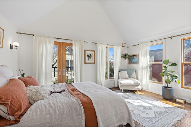 bedroom featuring access to exterior, multiple windows, french doors, and wood finished floors