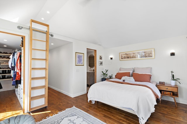 bedroom featuring a walk in closet, wood-type flooring, and vaulted ceiling