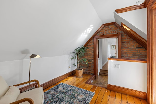 bonus room with baseboards, light wood-style floors, and vaulted ceiling