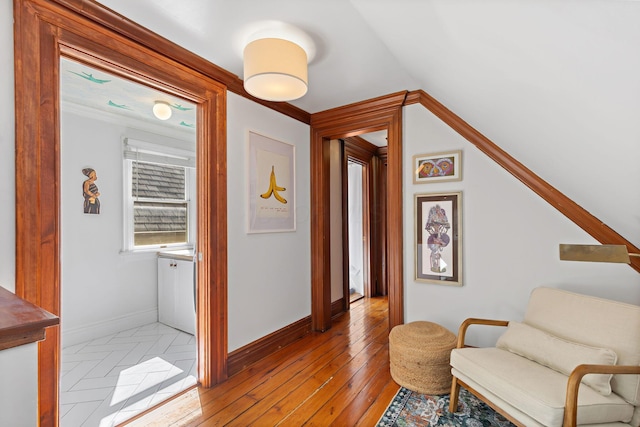 sitting room with crown molding, light wood-style floors, and baseboards