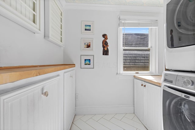 laundry room with baseboards, cabinet space, stacked washer and clothes dryer, and ornamental molding