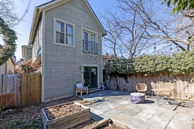 rear view of house with entry steps, a garden, a patio area, and a fenced backyard