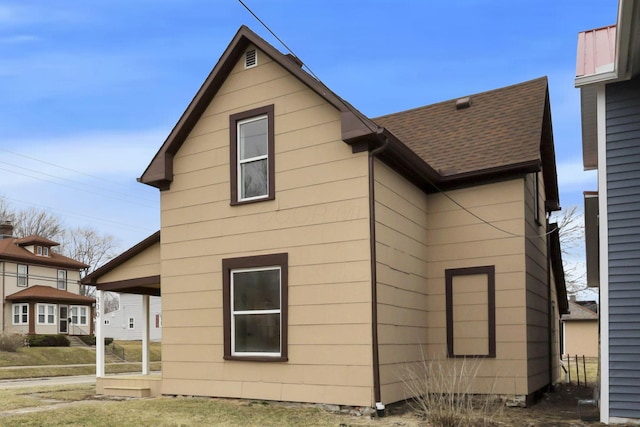 view of side of property with roof with shingles